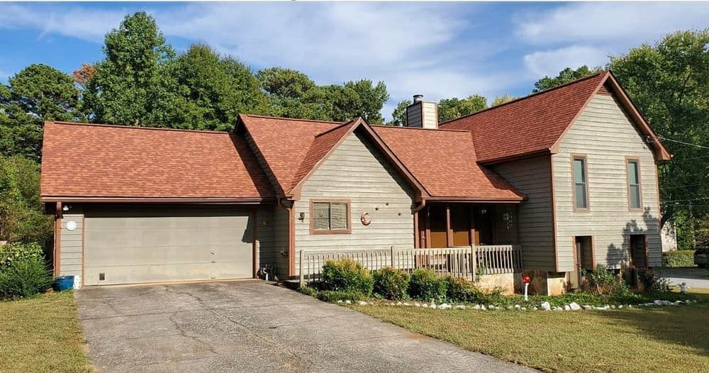 Charming two-story house with a brown roof, landscaped front yard, and attached garage.