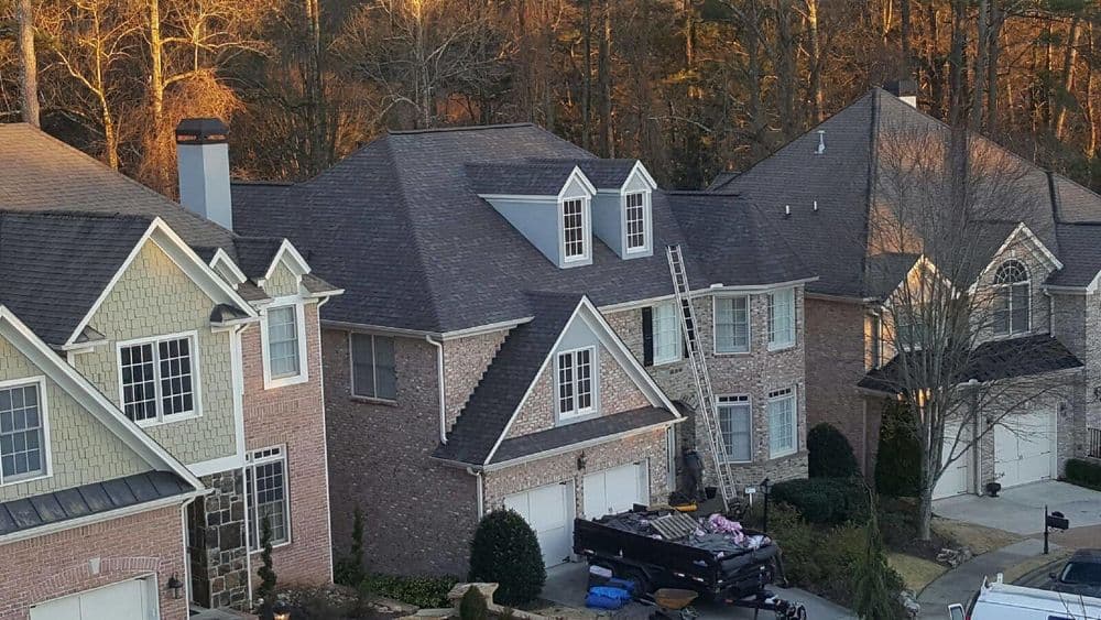 Aerial view of suburban homes with brick facades and landscaped yards at sunset.