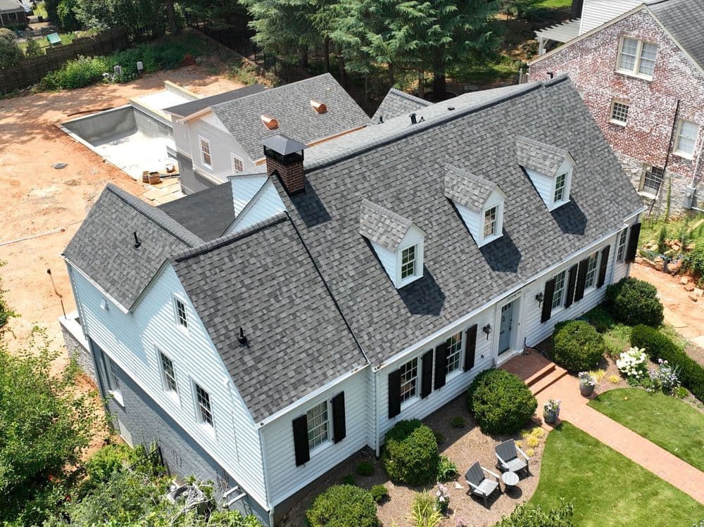 Aerial view of a charming blue house with a gray shingle roof and landscaped yard.