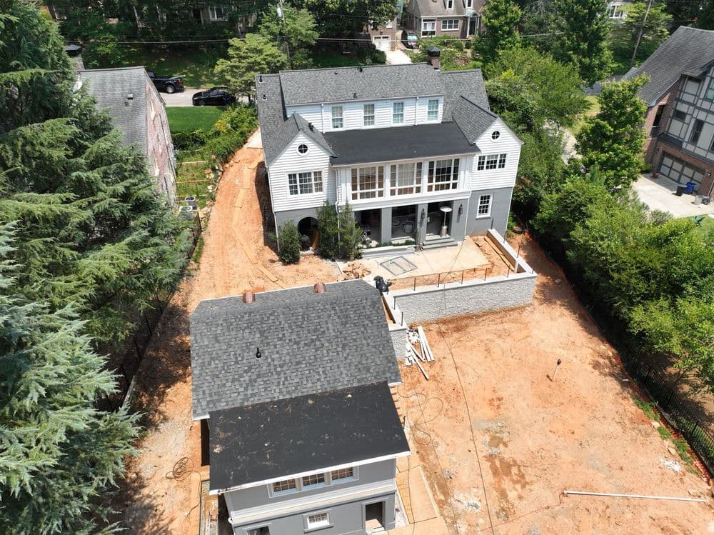 Aerial view of a gray house with a large deck and construction site in the yard.