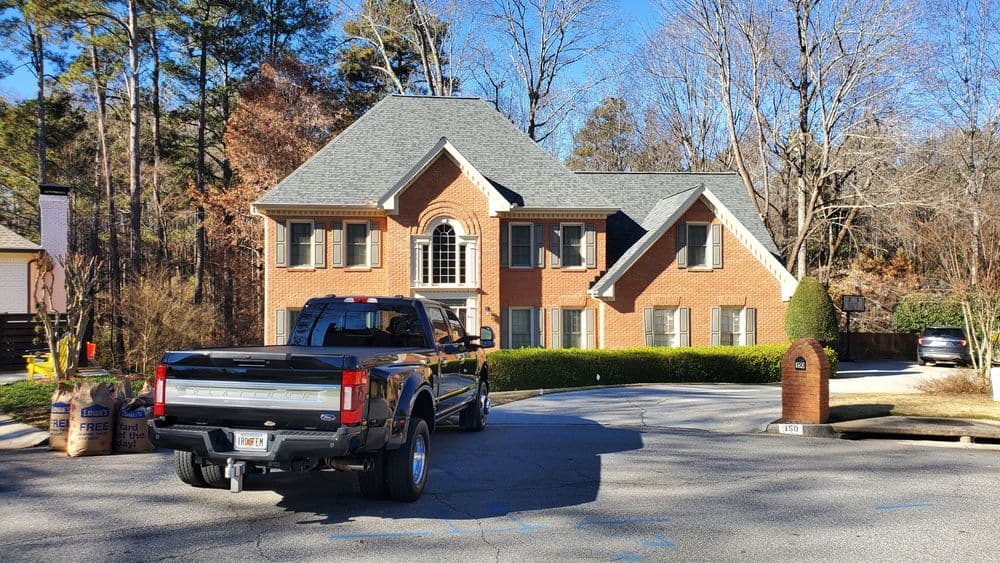 Brick house with a large front yard and a black pickup truck parked in the driveway.